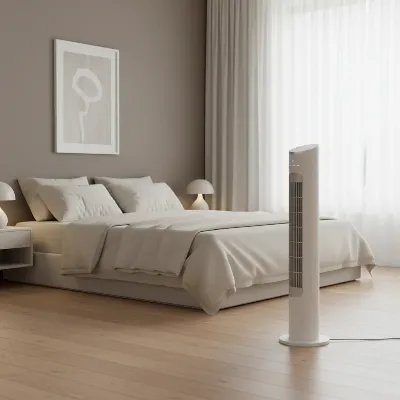 A sleek, minimalist white tower fan operating quietly in a modern bedroom setting.